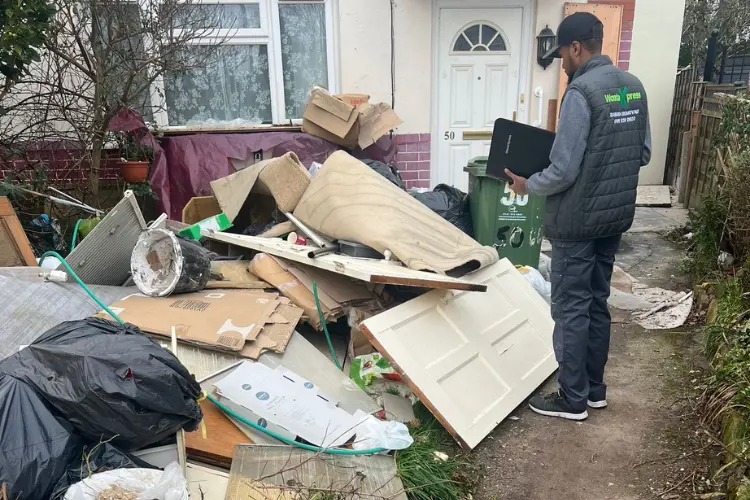WasteXpress team member assessing illegally dumped furniture and rubbish before removal in Manchester.
