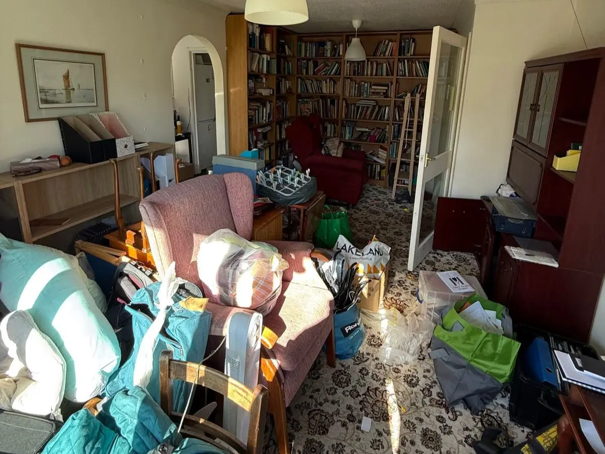 Cluttered living room filled with furniture and household items before house clearance and removal.