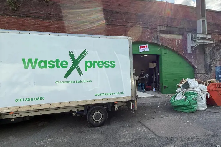 WasteXpress van collecting bagged commercial waste from a business premises in Manchester.