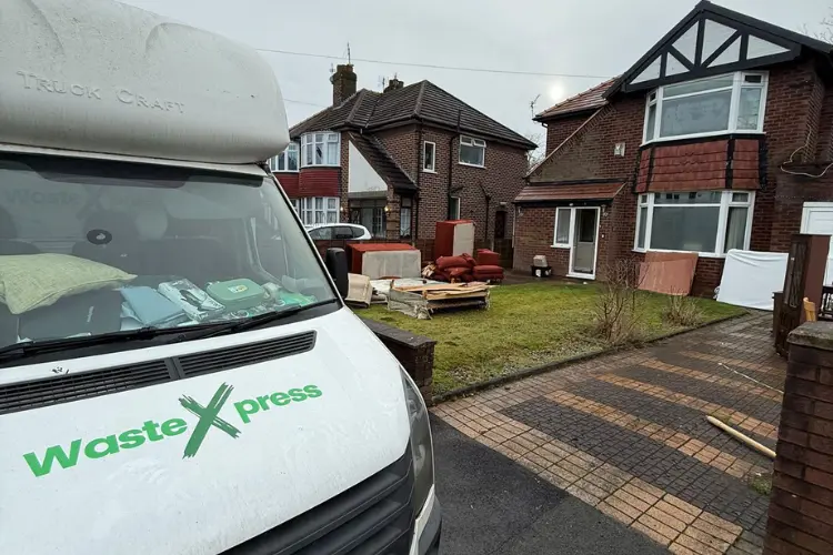 WasteXpress clearance van outside a Manchester home with furniture and household items ready for removal.