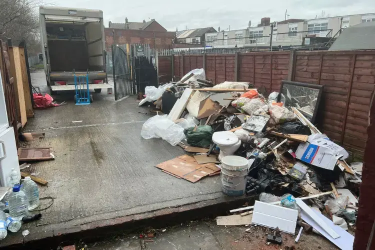 Waste collection vehicle beside a large pile of rubbish ready for a wait and load removal service in Manchester.