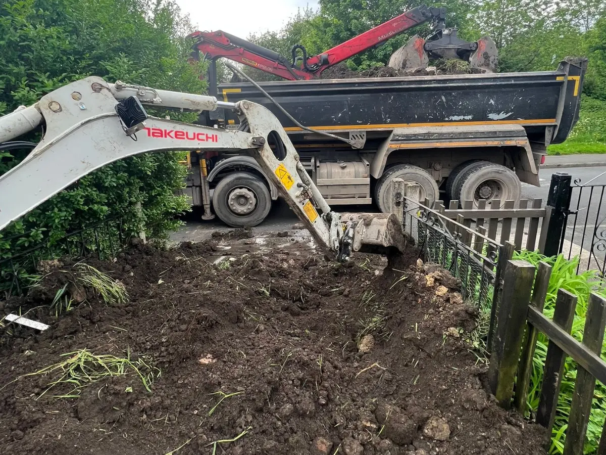 Excavator loading excess soil and garden waste into a grab lorry for collection and recycling.