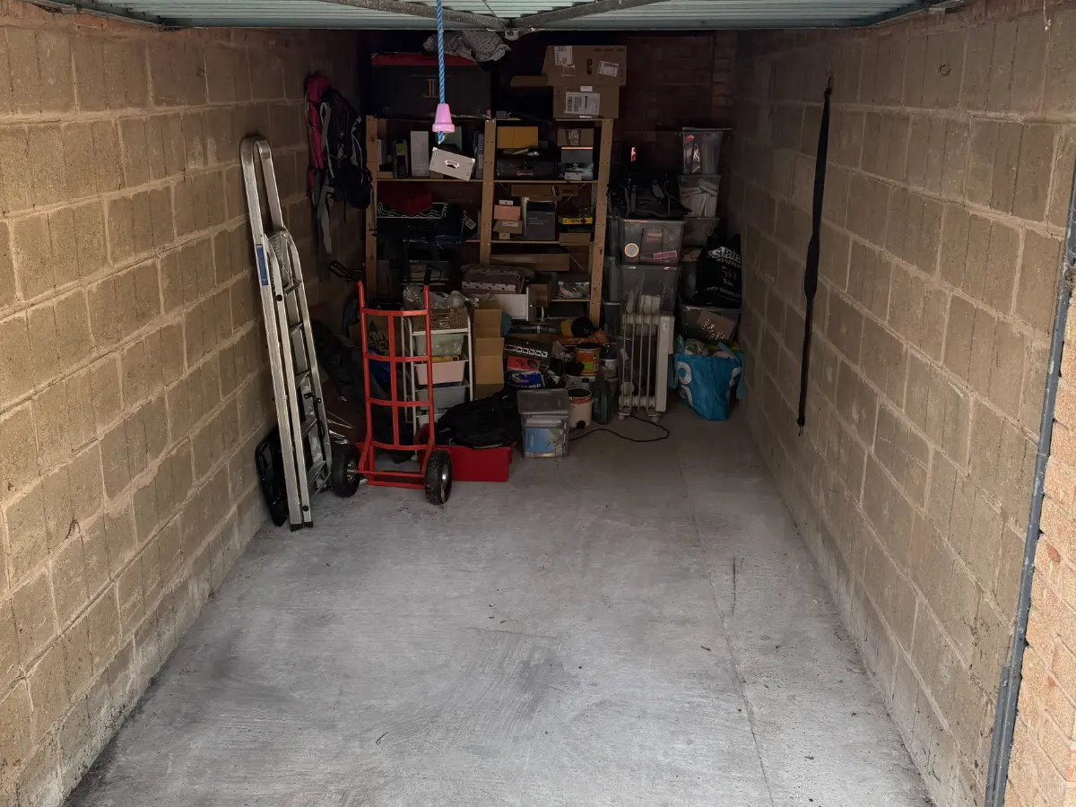 Storage unit filled with boxes, shelving, tools and household belongings before clearing out unwanted items.