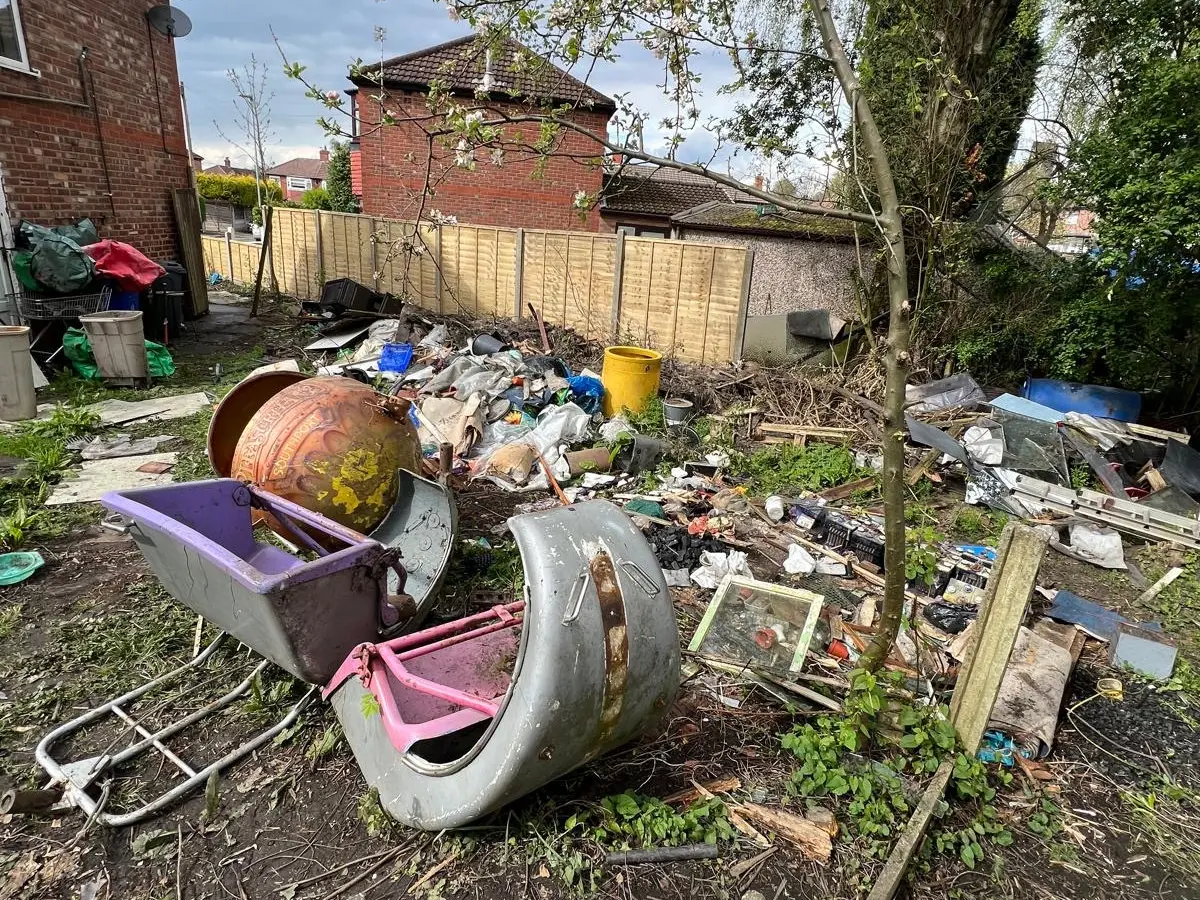Overgrown garden filled with rubbish, discarded items, branches, and garden waste before a professional garden clearance service.